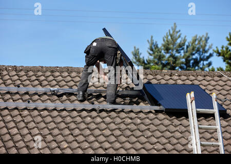 Mann, die Installation auf dem Dach Solarpanel Array in einer inländischen Solar-Panel-Installation im Vereinigten Königreich Stockfoto