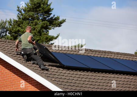 Mann, die Installation auf dem Dach Solarpanel Array in einer inländischen Solar-Panel-Installation im Vereinigten Königreich Stockfoto