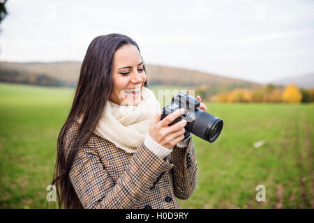 Schöne junge Frau mit Kamera fotografieren. Herbst Natur Stockfoto