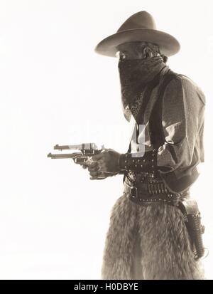 Seitenansicht der Verbrecher in Cowboy Kostüm Waffen über weißem Hintergrund halten Stockfoto