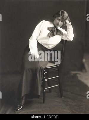 Nachdenkliche Frau auf Stuhl sitzend Stockfoto