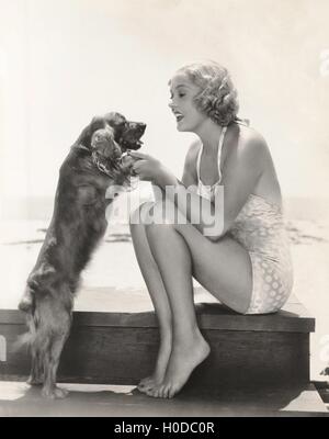 Junge Frau mit Cocker Spaniel am Strand spielen Stockfoto