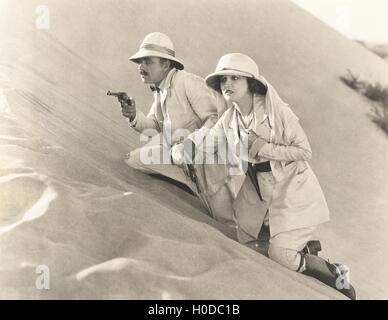 Bewaffneten paar Sanddüne Erklimmen Stockfoto