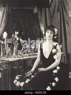 Porträt der Frau, geschmückt mit Blumen sitzt am Schminktisch Stockfoto