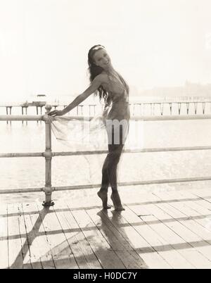 Frau im Badeanzug auf Zehenspitzen posiert am pier Stockfoto