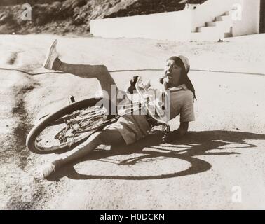 Frau, die ihr Fahrrad am Straßenrand herunterfallen Stockfoto