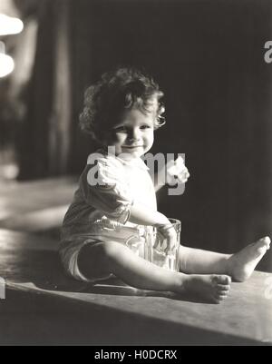 Baby Boy mit seiner Hand in ein Bierglas Stockfoto