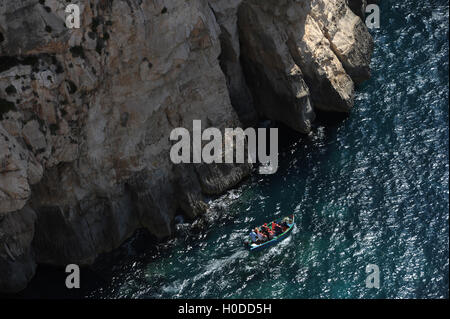 Eine traditionelle maltesische Luzzu nimmt Touristen rund um die Blue Grotto Caves und Klippen in Wied Iz-Zurrieq, Malta Stockfoto