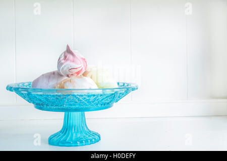 In Pastelltönen gestalteten Meringue Foto auf ein helles türkis Glas Kuchen stehen auf einem weißen Holz Anrichte. Stockfoto