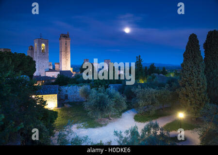San Gimignano auf Nacht, mittelalterlichen Wahrzeichen. Mond Licht auf Türmen und Park mit Zypressen und Olivenbäumen. Toskana, Italien, Euro Stockfoto