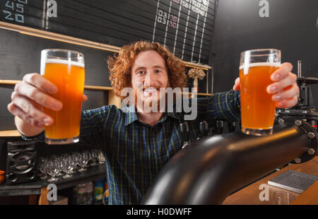 Glücklich lächelnd Barkeeper halten zwei Biergläser, Stand am Schalter, Barkeeper servieren bestellen Stockfoto