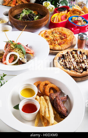 Spezialmenü mit gebratener Tintenfisch, Garnelen, Pizza, Meeresfrüchte-Suppe-Buffet auf dem Tisch Stockfoto