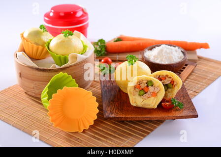 Huhn chinesische Knödel mit Karotten, in Scheiben geschnittenen Tomaten und Kräuter auf Holz Bambus Tablett Stockfoto