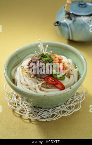 Koreanisch Bulgogi Kimchi Udon in Schüssel mit Teekanne auf dem Tisch Stockfoto