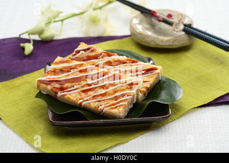 Echte fester Okonomiyaki an grünen Blatt und schwarze Platte im japanischen restaurant Stockfoto