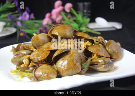 Pikante Muscheln mit Gemüse auf weißen Teller in schwarzem Hintergrund Stockfoto