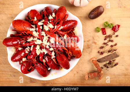 Roten Langusten Knoblauch auf weißen Teller mit Gewürzen auf Holztisch Stockfoto