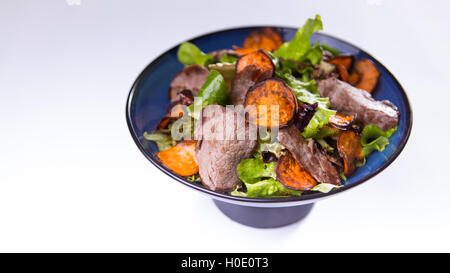 Rindfleischsalat mit Süßkartoffeln in blaue chinesische Schüssel auf weißem Hintergrund Stockfoto