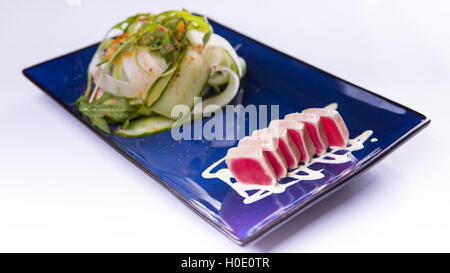 Salat mit Thunfisch Tataki auf blauen chinesischen Teller auf weißem Hintergrund Stockfoto