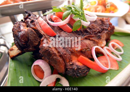 Die ganze Lammbraten mit Chili, Zwiebeln und Kräutern auf Bananenblatt Stockfoto