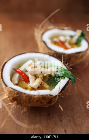 Kokos-Huhn-Suppe mit Chili und Kräutern auf Holztisch Stockfoto