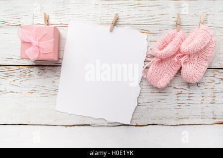 Rosa Baby Schühchen. Kleine Mädchen Socke und leere Karte auf weißem Holz Hintergrund Stockfoto