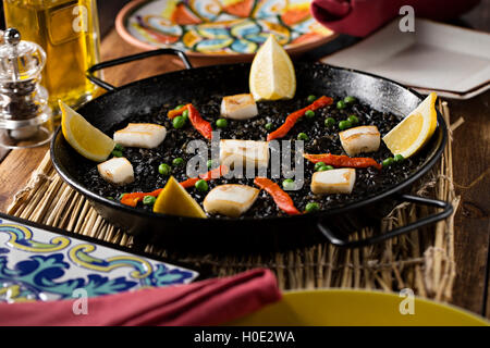 Gebratene Bohnen in schwarze Pfanne mit Zitrone, Chili und Käse auf Tablett aus Holz Stockfoto