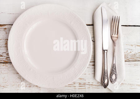 Teller, Gabel und Messer auf weißer Holztisch Stockfoto