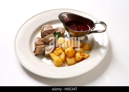 Rentier-Zunge mit Bratkartoffeln und Tomatensauce auf weißen Teller im restaurant Stockfoto