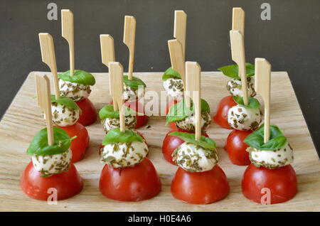 Spieße mit Fischbällchen mit in Scheiben geschnittenen Tomaten und Kräutern für den italienischen Sommer auf Holztisch Stockfoto