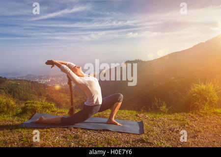 Sportlich fit Frau Praktiken Yoga Anjaneyasana in Bergen Stockfoto