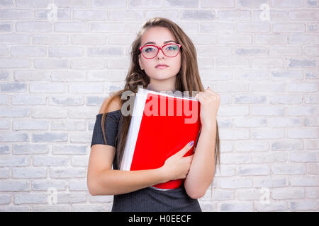 Junge schöne Mädchen Modell mit langen Haaren imitiert, Geschäftsfrau, Office Manager oder Administrator mit roten Ordner "Dokumente" Stockfoto