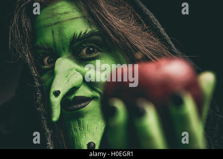 Grüne Hexe mit einem Apfel in der Hand. Geringe Schärfentiefe. Stockfoto