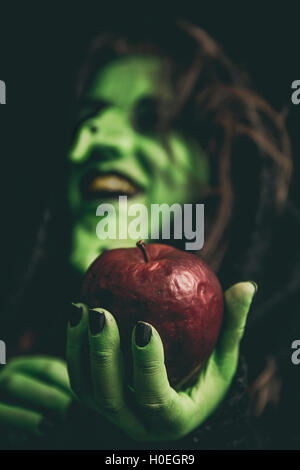 Hexe grün Hand hält einen faulen Apfel roten beim Lachen. Geringe Schärfentiefe. Stockfoto