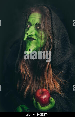 Grüne Hexe mit langen Haaren mit ein fauler Apfel in der Hand Stockfoto