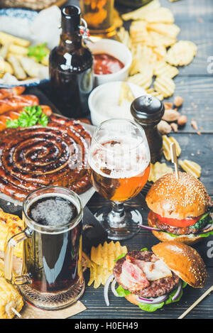 Bier und Brotzeit festgelegt. Oktoberfest-Essen-Frame-Konzept. Vielzahl von Bieren, gegrillte Würstchen, Burger, Pommes frites, Mais, Chips und s Stockfoto