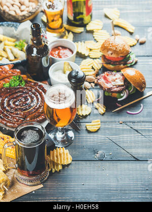 Bier und Brotzeit festgelegt. Oktoberfest-Essen-Frame-Konzept. Bier-Sortiment, gegrillte Würstchen, Burger, Pommes frites, Mais, Chips und s Stockfoto