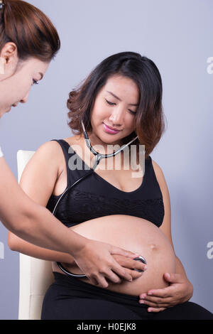 Bauch einer schwangeren Frau, die mit einem Stethoskop untersucht Stockfoto