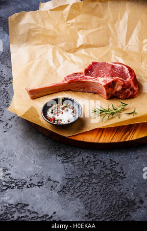 Rohes Frischfleisch Kalbfleisch Rib Steak mit Knochen und Gewürzen auf dunklem Hintergrund Textfreiraum Stockfoto