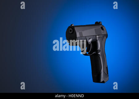 Schwarze Pistole seitwärts auf blauem Hintergrund isoliert Stockfoto