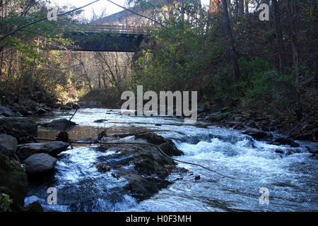 Blick auf den Wanderweg über den Bach im öffentlichen Park. Blackwater Creek in Hollins Mill Park, Lynchburg, Virginia, USA Stockfoto