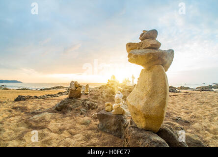 Steinen Pyramide auf Sand als Symbol für Zen, Harmonie und Balance. Meer bei Sonnenuntergang in Khao Lak Thailand Stockfoto