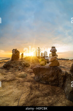 Steinen Pyramide auf Sand als Symbol für Zen, Harmonie und Balance. Meer bei Sonnenuntergang in Khao Lak Thailand Stockfoto