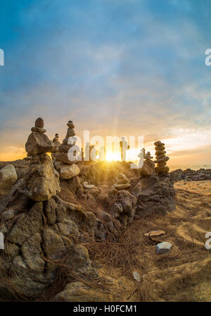 Steinen Pyramide auf Sand als Symbol für Zen, Harmonie und Balance. Meer bei Sonnenuntergang in Khao Lak Thailand Stockfoto