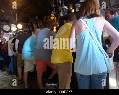 Gäste in bunten Hemden schlanke über bar und trinken Bier Stockfoto