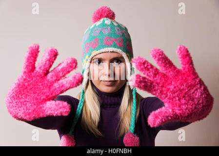Frau trägt eine Strickmütze und ein rosa warme Handschuhe Strecken ihre Hände vor ihr Stockfoto