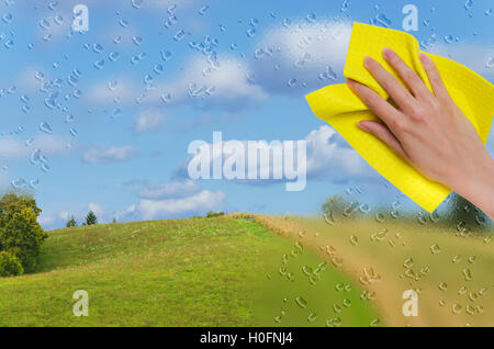 die Hand abwischen Regen aus dem Fenster offenbart eine wunderschöne Landschaft Stockfoto