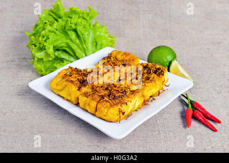 Gebratener Tofu mit Zitronengras auf weißen Teller mit Salat, Chili und Zitrone Stockfoto