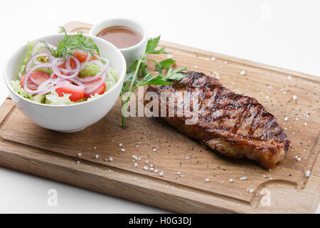 New York Steak mit Gemüsesalat auf Holzbrett Stockfoto