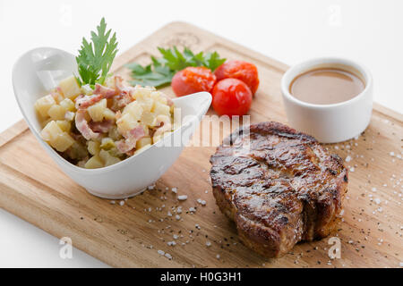 Schweinesteak mit deutschen Kartoffelsalat auf Holzbrett Stockfoto